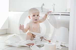 Adorable baby boy playing with toilet paper