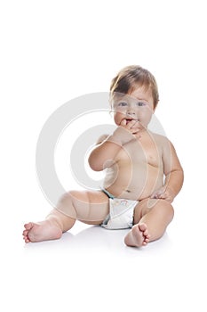 Adorable baby boy sitting with fingers in his mouth