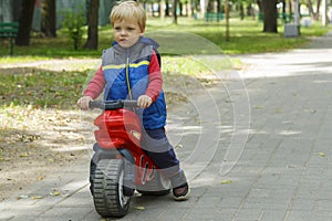 Adorable Baby Boy Sitting On A toy Motorcycle in the park. copy space