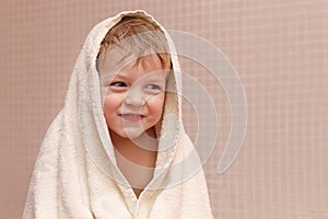 Adorable baby boy sitting under a hooded towel after bath.