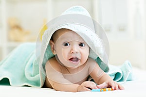 Adorable baby boy under a hooded towel after