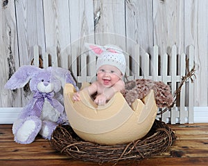 Adorable baby in bunny hat sitting in giant egg