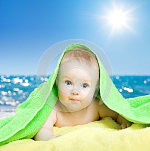Adorable baby in colorful towel on sea beach