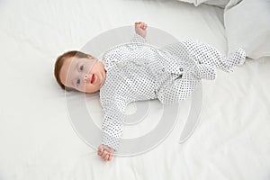 Adorable baby in cute footie on white sheet