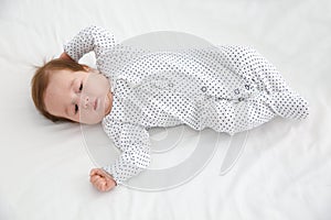 Adorable baby in cute footie on white sheet
