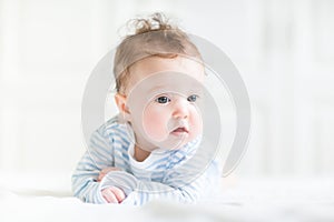 Adorable baby doing her tummy time in a white nursery