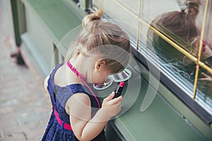 Adorable baby in a dress paints lips with lipstick