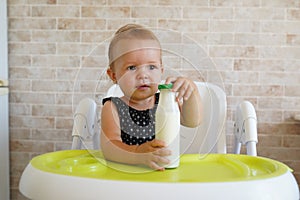 Adorable baby drinking milk from a bottle from bottle. Formula drink for infant. Kitchen