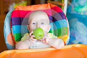 Adorable baby eating apple in high chair