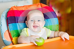 Adorable baby eating apple in high chair