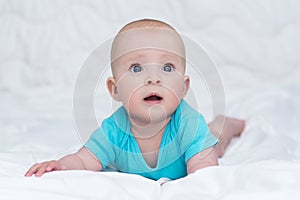 Adorable baby girl or boy in blue shirt with big blue eyes, indoors
