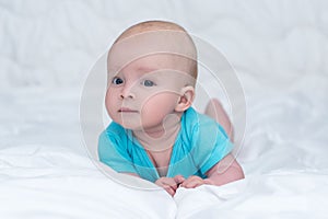 Adorable baby girl or boy in blue shirt with big blue eyes, indoors