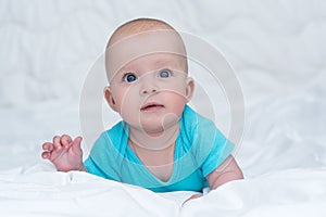 Adorable baby girl or boy in blue shirt with big blue eyes, indoors