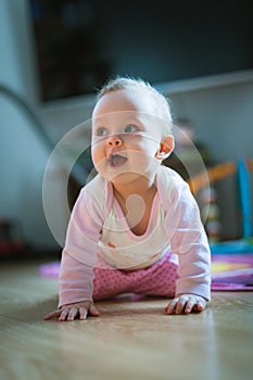 Adorable baby girl crawls on all fours floor at