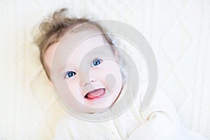 Adorable baby girl with curly hair on a white cabl