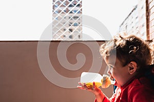 Adorable baby girl drinking milk from her bottle isolated outdoors