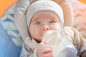 Adorable baby girl drinks formula milk from bottle