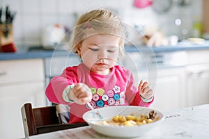 Adorable baby girl eating from fork vegetables and pasta. food, child, feeding and development concept. Cute toddler