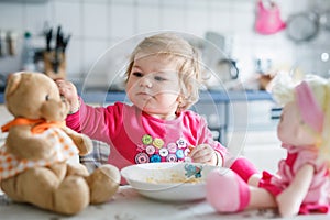 Adorable baby girl eating from fork vegetables and pasta. food, child, feeding and development concept. Cute toddler