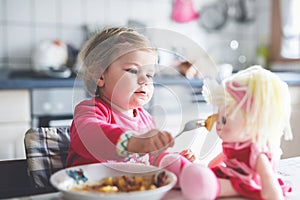 Adorable baby girl eating from fork vegetables and pasta. food, child, feeding and development concept. Cute toddler