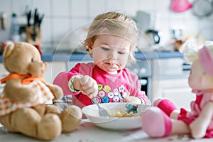 Adorable baby girl eating from fork vegetables and pasta. food, child, feeding and development concept. Cute toddler