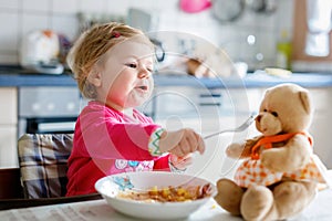 Adorable baby girl eating from fork vegetables and pasta. food, child, feeding and development concept. Cute toddler