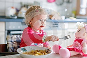 Adorable baby girl eating from fork vegetables and pasta. food, child, feeding and development concept. Cute toddler