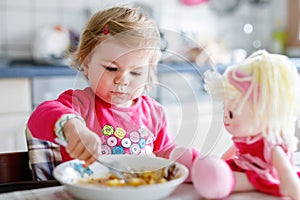 Adorable baby girl eating from fork vegetables and pasta. food, child, feeding and development concept. Cute toddler