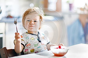 Adorable baby girl eating from spoon fresh healthy raspberries food, child, feeding and development concept. Cute