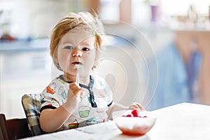 Adorable baby girl eating from spoon fresh healthy raspberries food, child, feeding and development concept. Cute