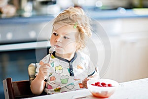 Adorable baby girl eating from spoon fresh healthy raspberries food, child, feeding and development concept. Cute