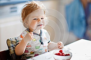 Adorable baby girl eating from spoon fresh healthy raspberries food, child, feeding and development concept. Cute