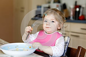 Adorable baby girl eating from spoon mashed vegetables and puree. food, child, feeding and development concept -cute
