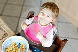 Adorable baby girl eating from spoon mashed vegetables and puree. food, child, feeding and people concept