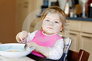 Adorable baby girl eating from spoon mashed vegetables and puree. food, child, feeding and people concept