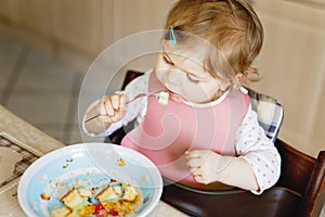 Adorable baby girl eating from spoon mashed vegetables and puree. food, child, feeding and people concept