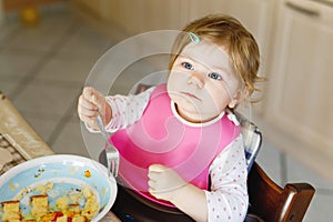 Adorable baby girl eating from spoon mashed vegetables and puree. food, child, feeding and people concept