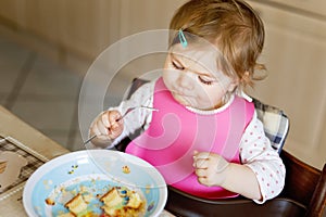 Adorable baby girl eating from spoon mashed vegetables and puree. food, child, feeding and people concept