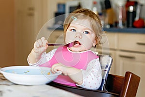 Adorable baby girl eating from spoon mashed vegetables and puree. food, child, feeding and people concept