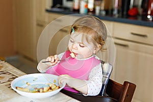 Adorable baby girl eating from spoon mashed vegetables and puree. food, child, feeding and people concept