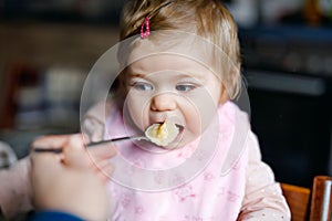 Adorable baby girl eating from spoon mashed vegetables and puree. food, child, feeding and people concept -cute toddler