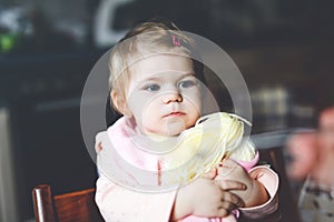 Adorable baby girl eating from spoon mashed vegetables and puree. food, child, feeding and people concept -cute toddler