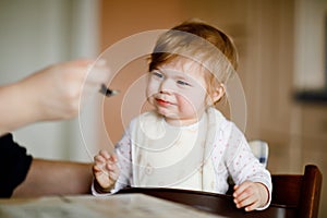 Adorable baby girl eating from spoon mashed vegetables and puree. food, child, feeding and people concept -cute toddler