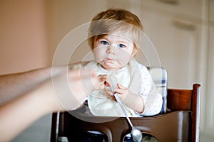 Adorable baby girl eating from spoon mashed vegetables and puree. food, child, feeding and people concept -cute toddler