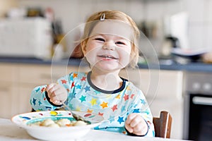 Adorable baby girl eating from spoon vegetable noodle soup. food, child, feeding and development concept. Cute toddler
