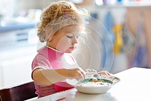 Adorable baby girl eating from spoon vegetable noodle soup. food, child, feeding and development concept. Cute toddler