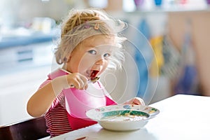 Adorable baby girl eating from spoon vegetable noodle soup. food, child, feeding and development concept. Cute toddler