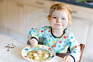 Adorable baby girl eating from spoon vegetable noodle soup. food, child, feeding and people concept
