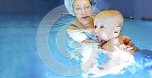 Adorable baby girl enjoying swimming in a pool with her mother early development class for infants teaching children to