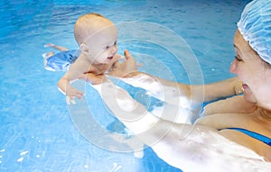 Adorable baby girl enjoying swimming in a pool with her mother early development class for infants teaching children to